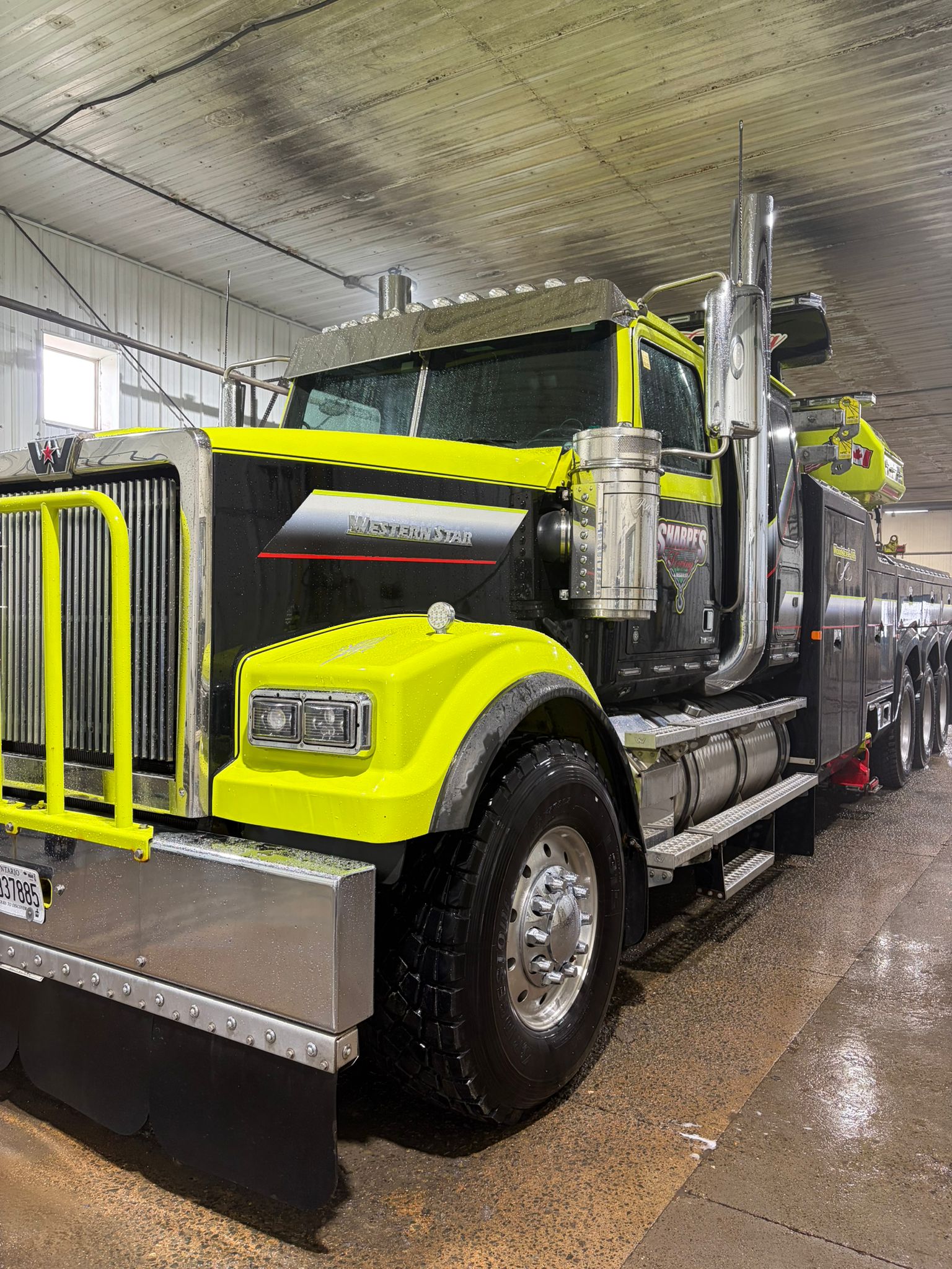 Front three-quarter view of a Sharpe's Towing lime green and black Western Star heavy-duty wrecker with a yellow bull bar and chrome accents.
