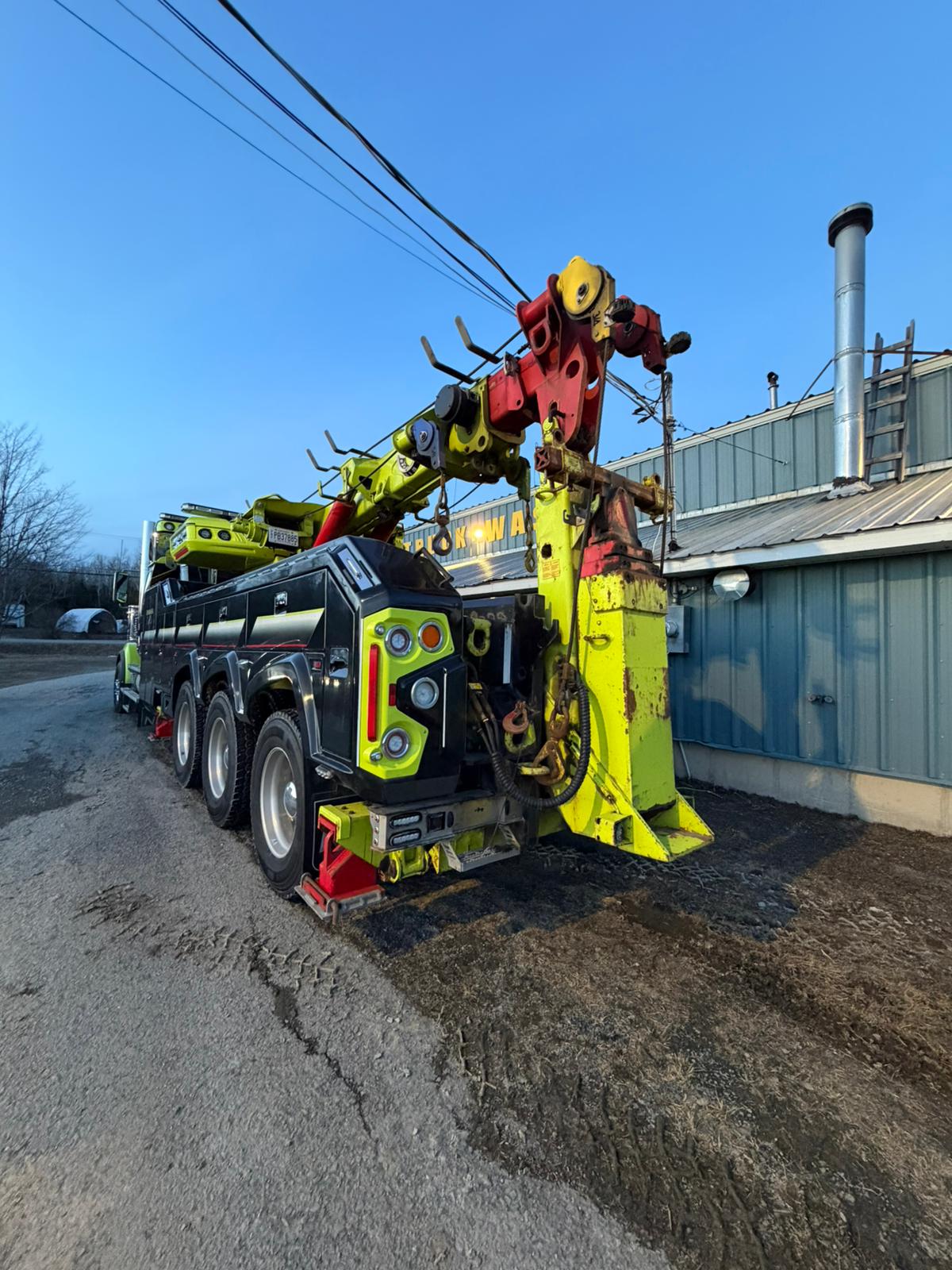 Rear view of Sharpest Towing heavy-duty rotator wrecker with lime green recovery boom.